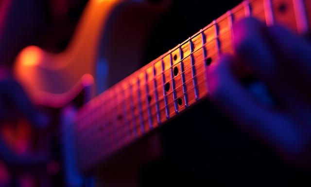 Close up of guitar fretboard with neon lighting
